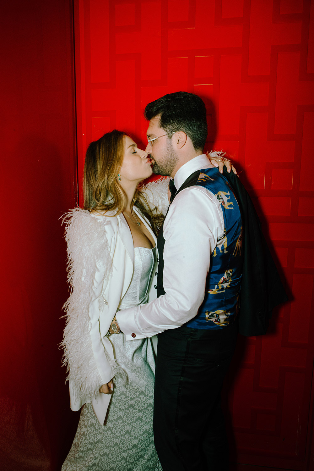 Newlsyweds pose in the red elevator at Antonio Park during their wedding while groom shoes off his snazzy dog printed vest and bride in her vintage white feathery jacket