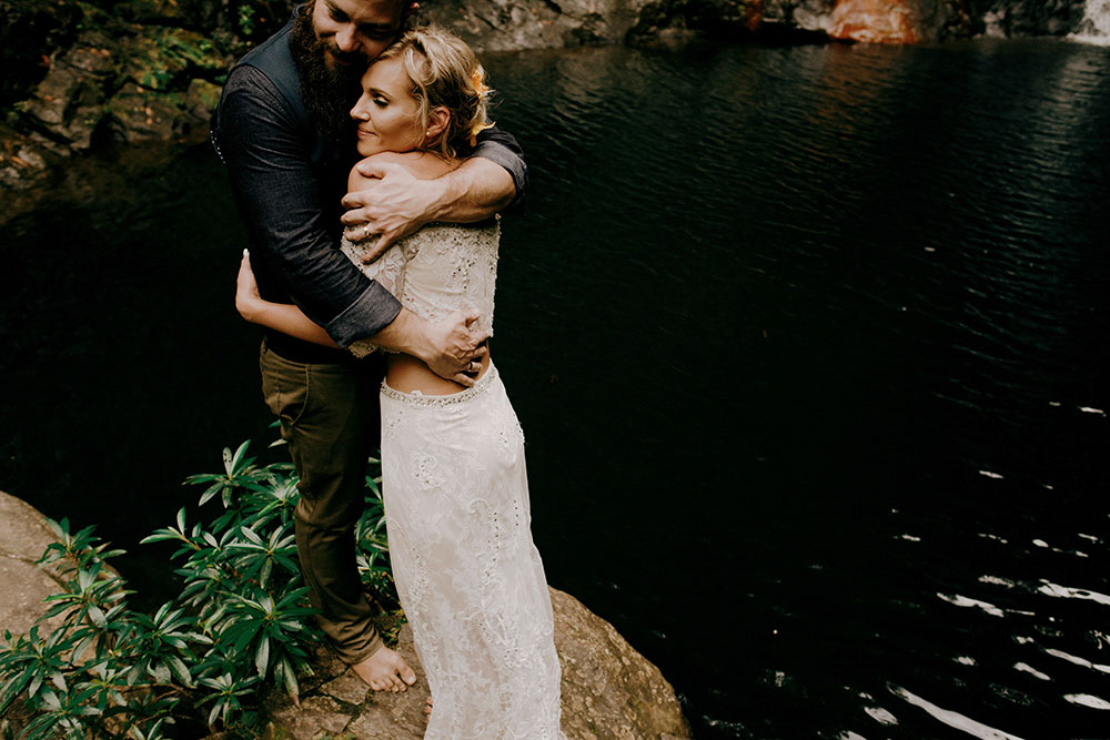 couple embrace after saying i do at the base of a waterfall in the jungle at this belize wedding