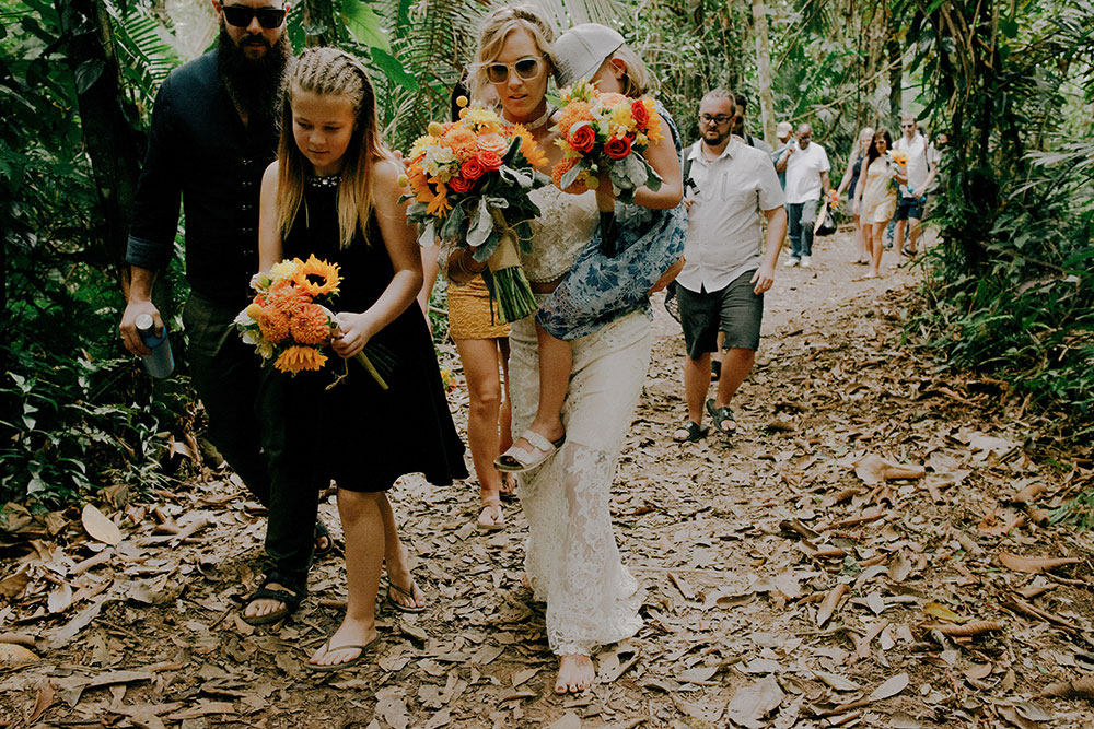 group walks up the mountain in the jungle at this belize wedding & bride carries daughter
