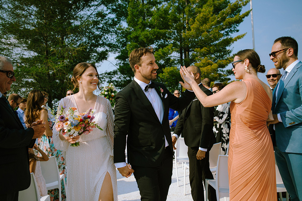 high five as newlyweds walk out of their ceremony held on the dock of their Northridge Inn Wedding