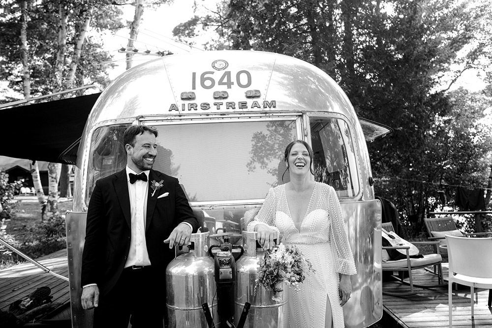 Bride and groom pose in a bloack and white photo in front of an air stream which is one of the unique rooms at the Northridge Inn resort, a gorgeous Muskoka resort and wedding 
venue. 