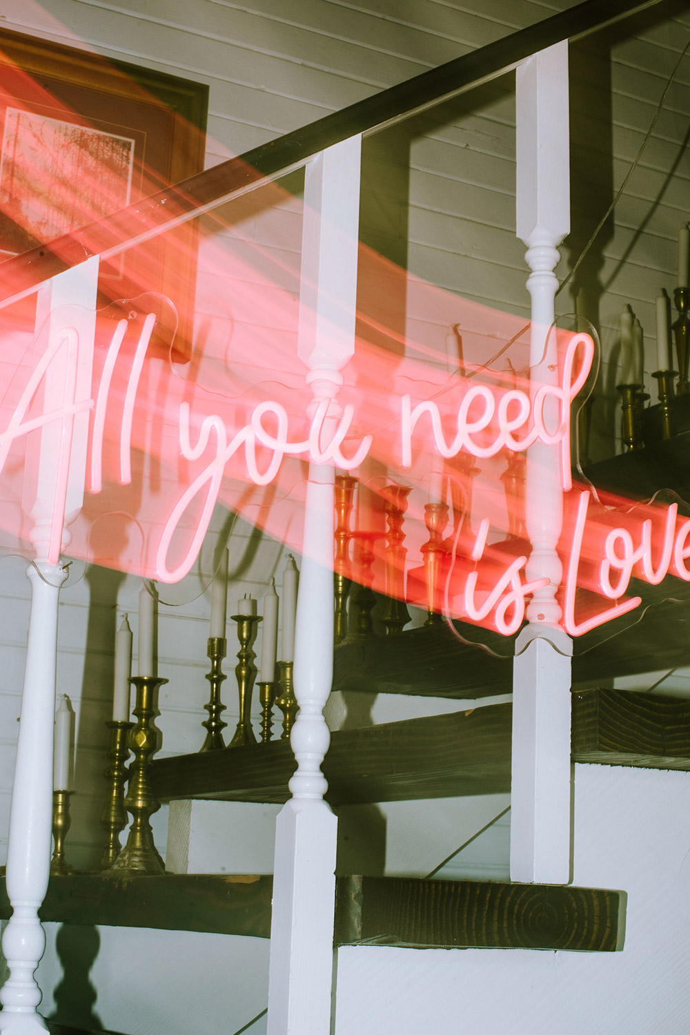 a neon sign that reads "all you need is Love" is caprtured using a shutter drag technique in the main dining room of the Northridge Resort wedding venue in Muskoka