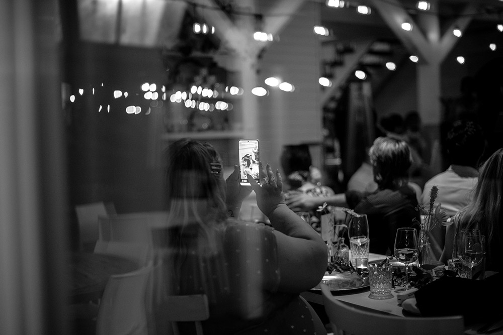 a woman captures a photo on her cell pohine during a speech at this Northridge Inn Wedding