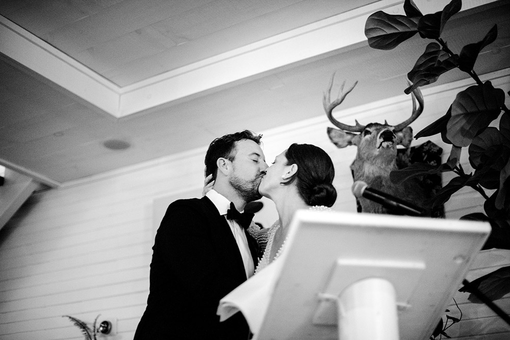 Newleyweds pause their speech to share a kiss at their wedding held in the main dining room of the Northridge Inn Resort in Muskoka Ontario
