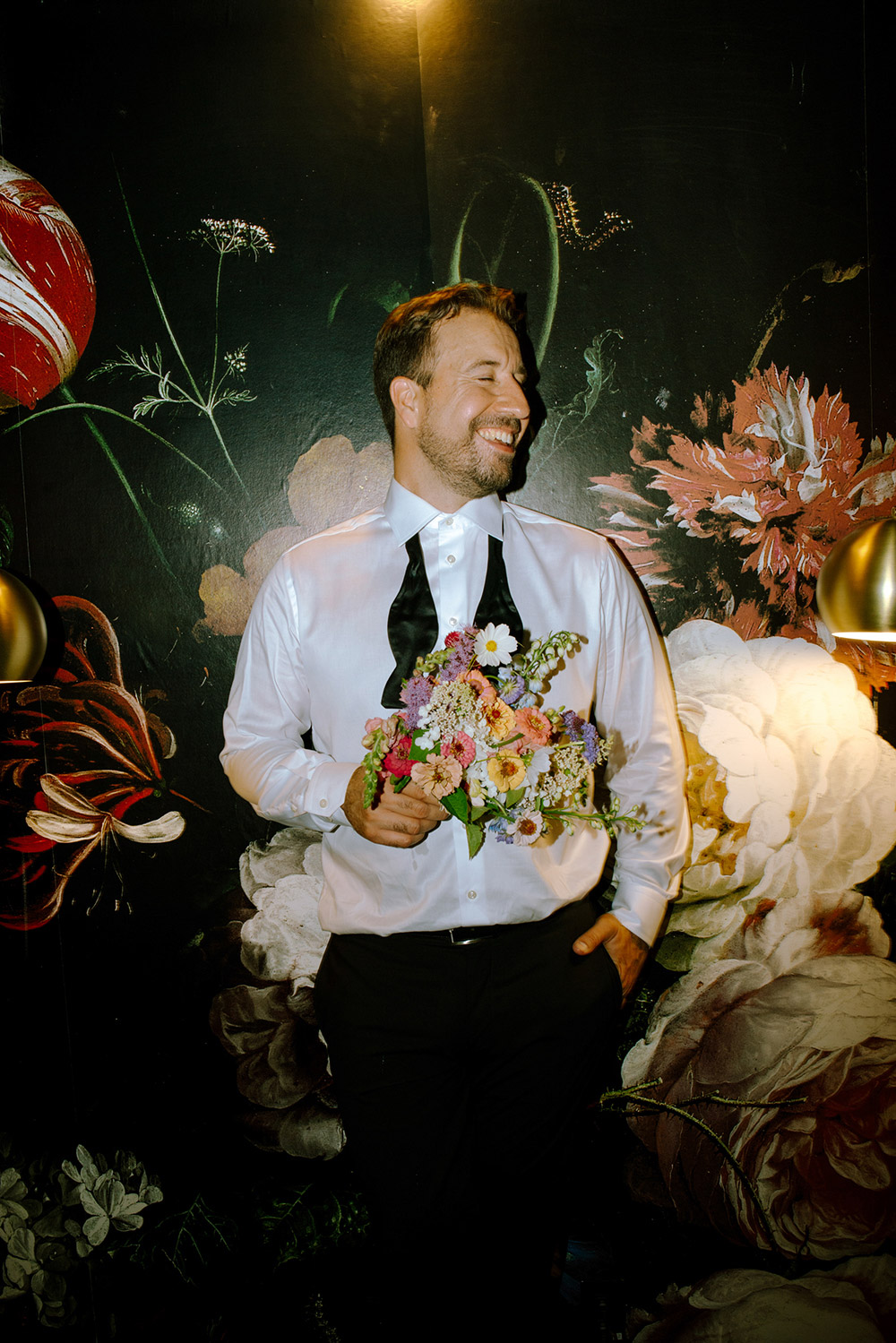 Groom laughs while holding the brides bouquet during a fun portrait session during his wedding reception which was held at the Northridge inn resort in Muskoka Ontario