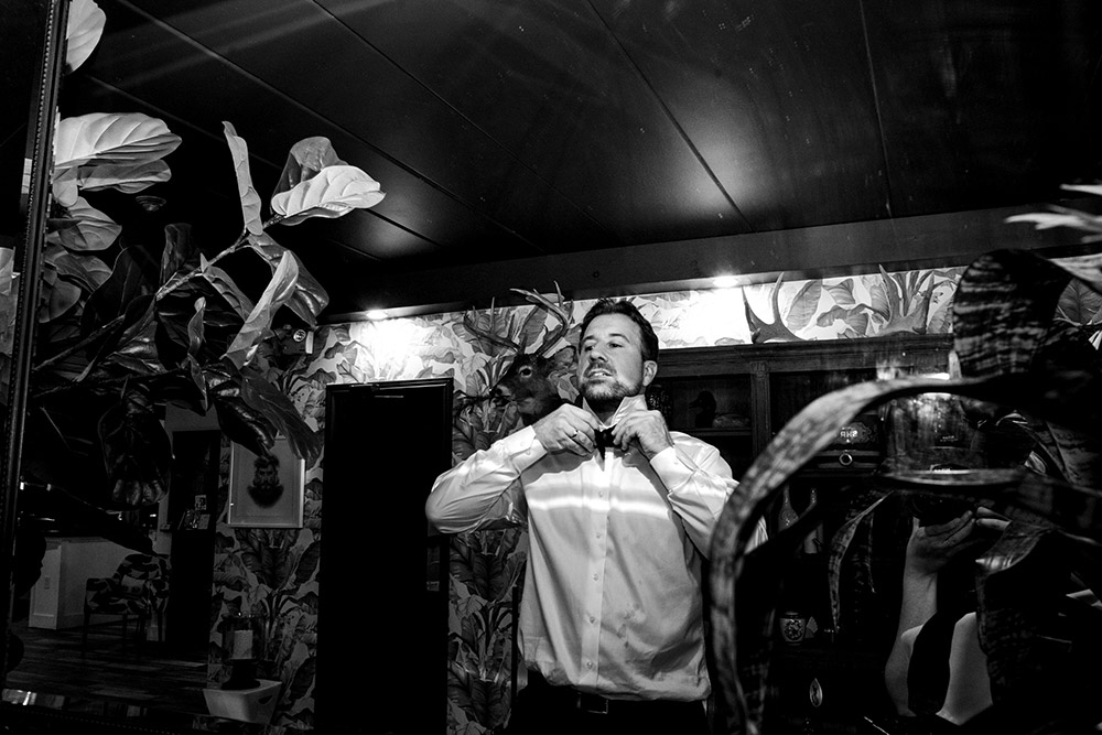 Groom adjusts his bow tie during the party at his Northridge Inn Wedding