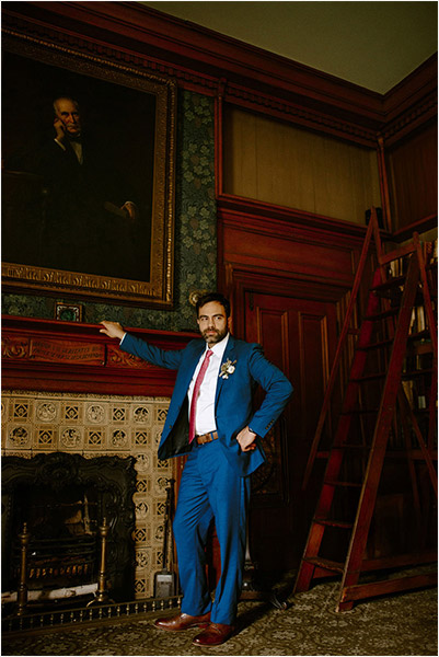 Toronto Art Gallery of Ontario Wedding Photography of a groom posing beneath a very regal looking renaissance painting on his wedding day at the library in the AGO