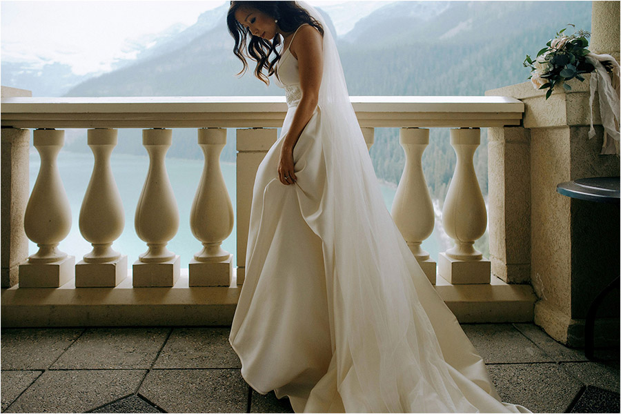 Chateau Lake Louise Wedding photography of a beautiful bride completing her getting ready stages on a Fairmont Balcony that overlooks the breathtaking Lake Louise mountains