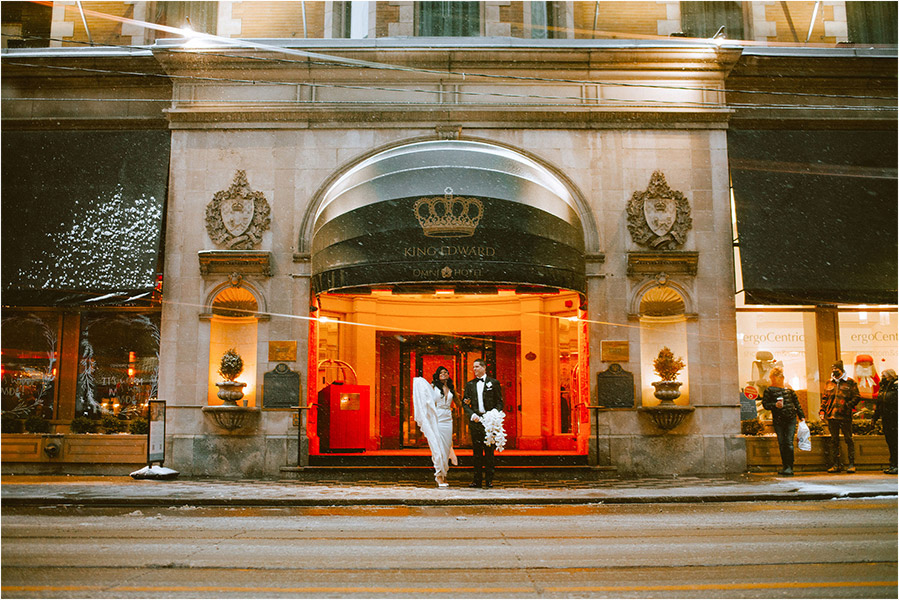 Omni King Edward Hotel Wedding Photography of a Wedding couple enduring the snowy weather just outside the entrance of the Omni King Edward Hotel on their wedding day