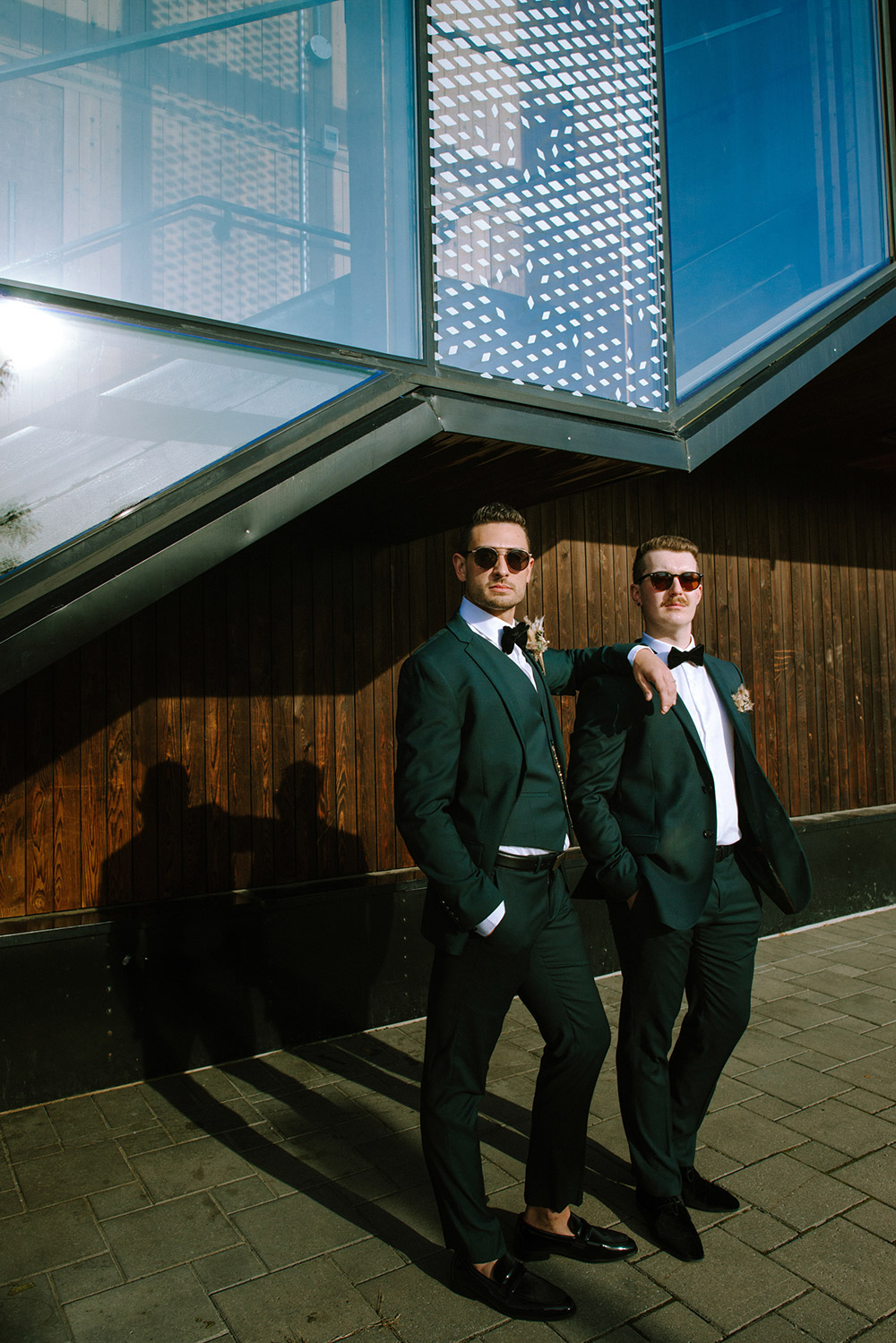 grooms poses with sunglasses on during a very sunny fall photos session at their science north wedding