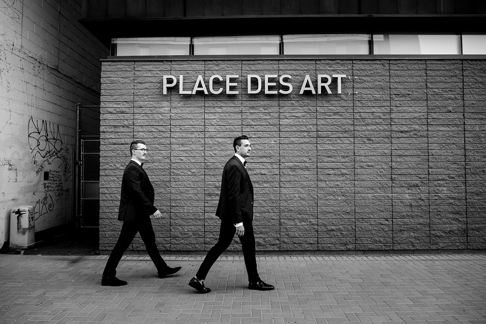 grooms walk under the sign that reads place des art in sudbury before heading to their science north wedding