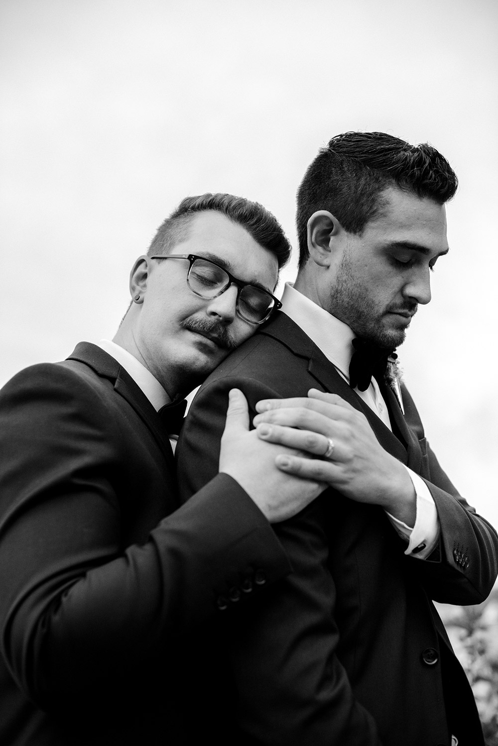 husbands pose one leaning on to the others back with eyes closed enjoying the love and happiness of their day at this science north wedding