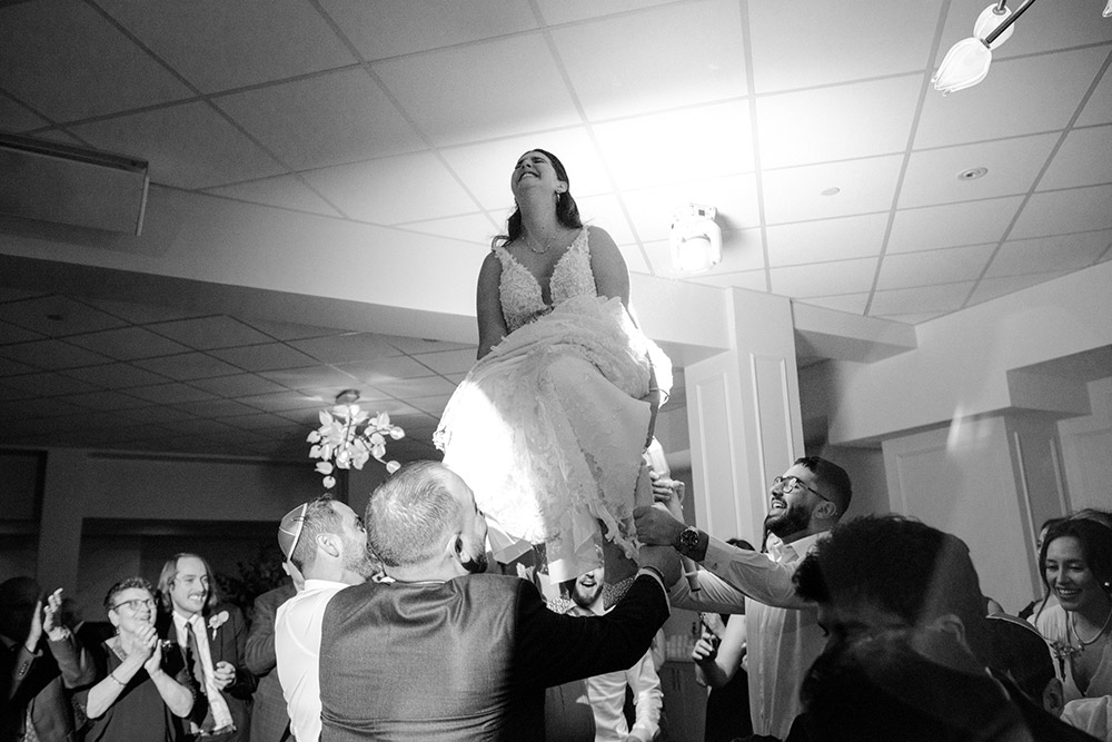 bride holdws tight on the sides of her chair during the hora dance at The Doctor's House Wedding