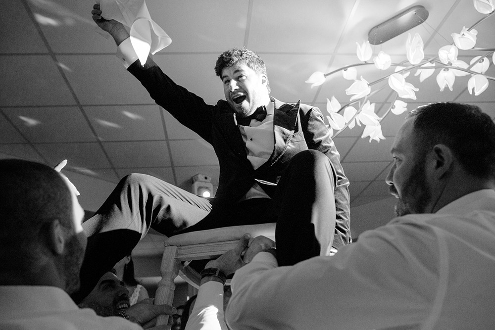 groom is raised high up on his chair during the hora dance at The Doctor's House Wedding