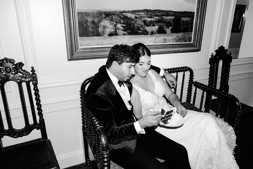 couple enjoys a slice of cake outside of the reception room at The Doctor's House Wedding