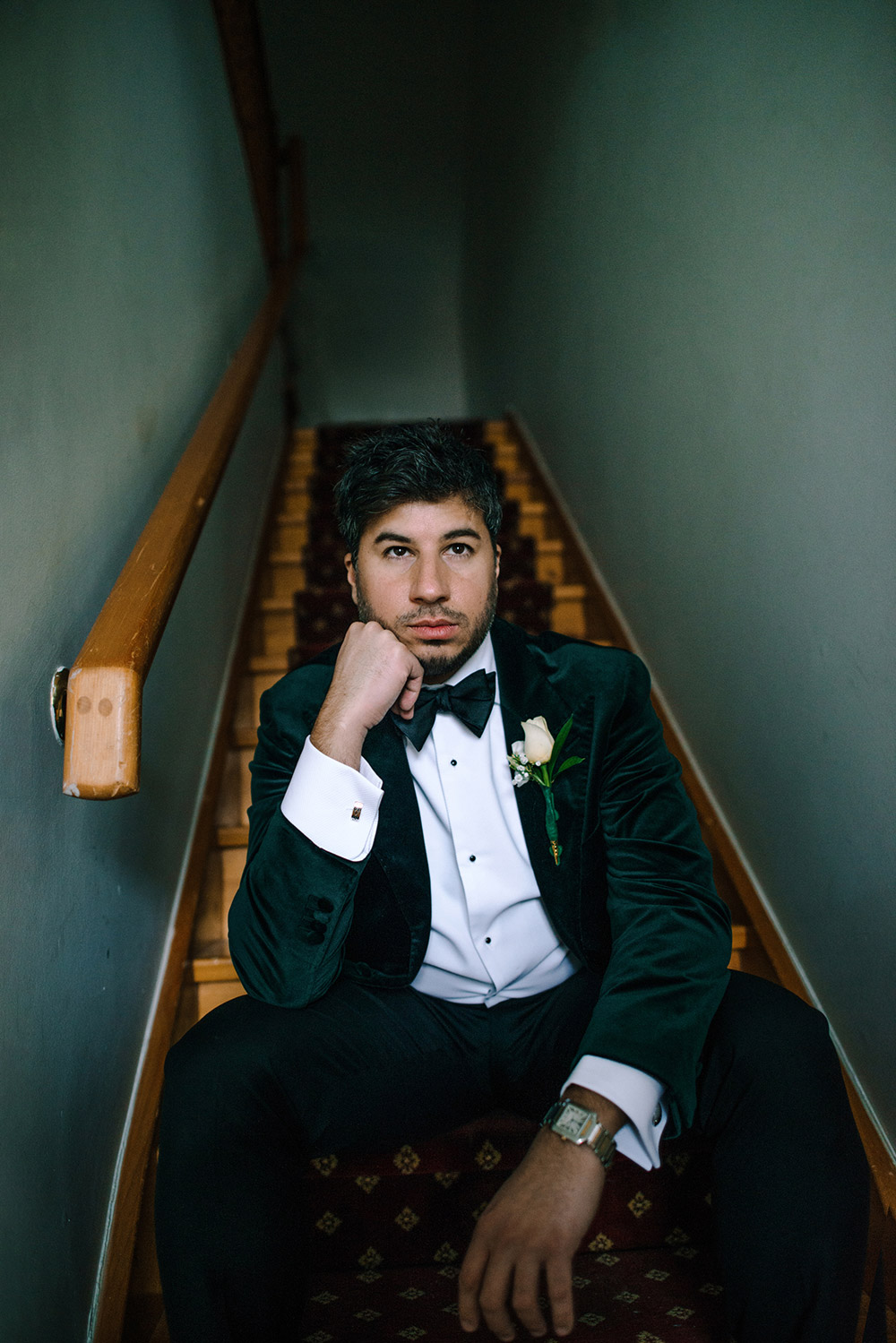 groom sits at the bottom of a staircase at The Doctor's House Wedding