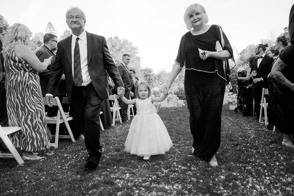 flower girl being walked down the aisle by grandparents at harding waterfront estate wedding