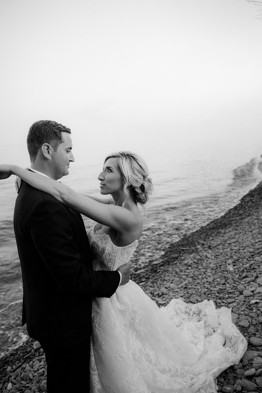 bride and groom embrace on the beach at sunset during their portrait session at this harding waterfront wedding